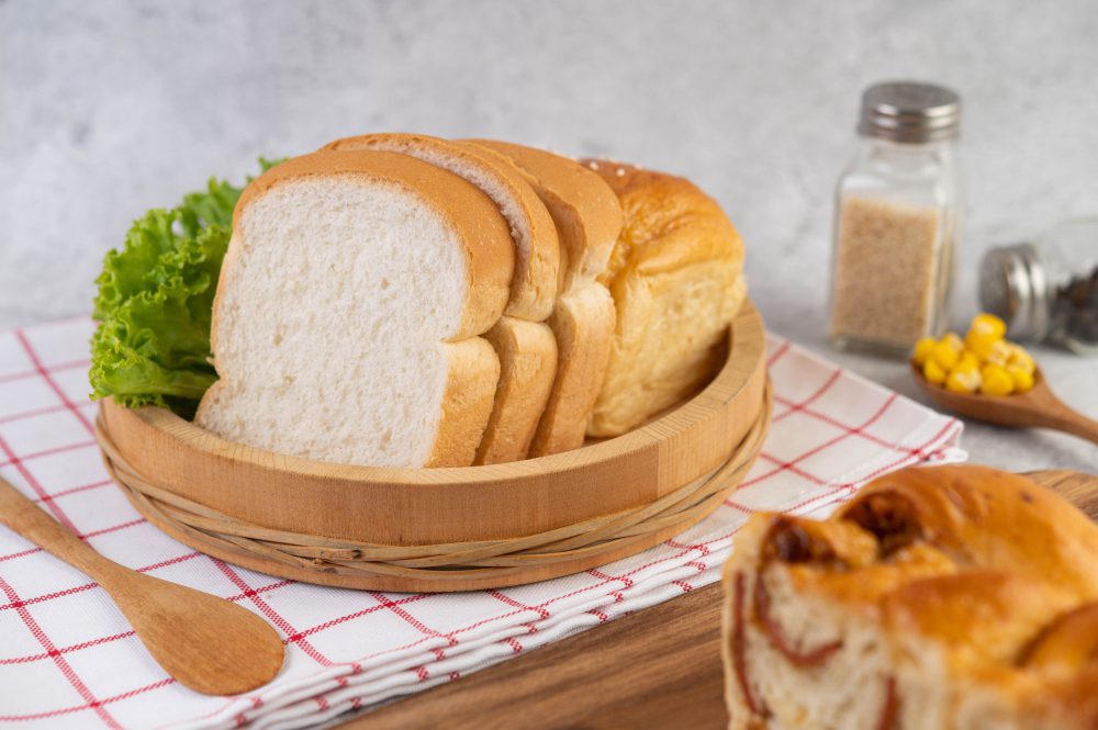 A basket of bread and some other food on the table.