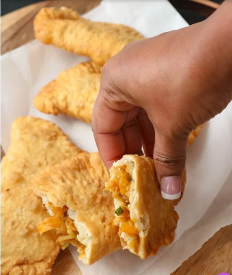 A person holding food in their hand over some cheese bread.