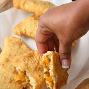 A person holding food in their hand over some cheese bread.
