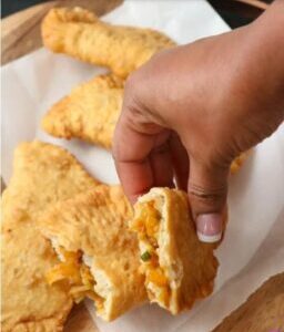 A person holding food in their hand over some cheese bread.