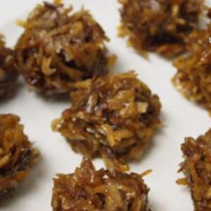 A white plate topped with lots of coconut covered cookies.