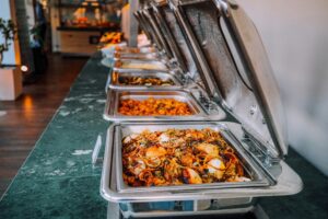 A row of buffet trays filled with food.